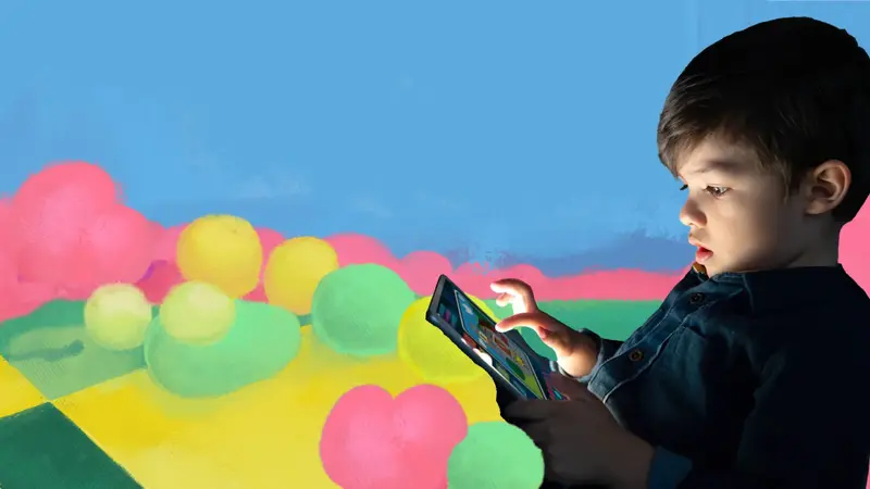 A young boy looking closely at a tablet as he taps the screen